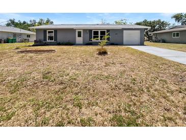 Charming single-story home with a well-maintained front yard, driveway, and attached garage at 837 Dolphin Nw Ave, Port Charlotte, FL 33948