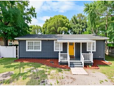 Charming single-story home with a yellow front door and manicured landscaping at 5004 E Seneca Ave, Tampa, FL 33617