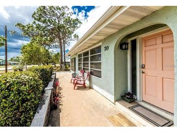 Charming home featuring a lovely, covered front porch with comfortable seating and an inviting coral-colored door at 70 Virginia Ct, Englewood, FL 34223