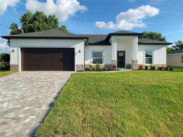 Charming single-story home with a well-manicured lawn, gray paver driveway, and neutral color scheme at 4150 Windsong Ave, North Port, FL 34287