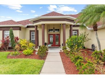 Charming single-story home with stucco exterior, a red tile roof, mature landscaping, and a covered front porch at 2818 Mossy Timber Trl, Valrico, FL 33596