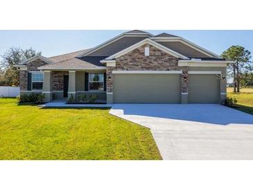 Beautiful single-story home featuring a three-car garage, stone accents, manicured lawn, and welcoming entryway at 6179 Notre Dame Ter, North Port, FL 34291