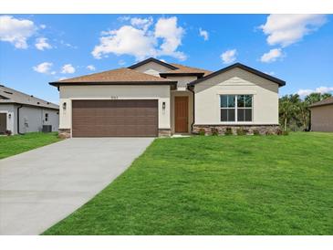 Charming single-story home featuring a well-manicured lawn and a two-car garage with brown doors at 5163 Arley Ct, North Port, FL 34288