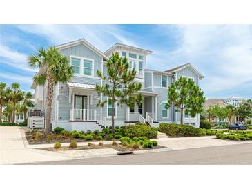 Charming two-story home featuring light blue siding, manicured landscaping, and a welcoming front porch and a palm tree at 283 Saint Lucia Dr # 202, Bradenton, FL 34209