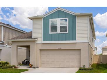 Two-story home featuring a two-car garage, covered porch and blue and tan color scheme at 34327 Verbena St, Wesley Chapel, FL 33545