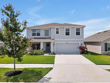 Charming two-story home with a well-manicured lawn, inviting entrance, and attached two-car garage at 5289 Fiddle Fig Ave, Wimauma, FL 33598