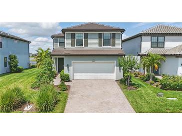 Charming two-story home with a well-maintained lawn, featuring a brick driveway and an attached two-car garage at 16231 Pine Mist Dr, Bradenton, FL 34211