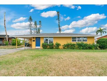 Charming single-story home featuring a well-maintained lawn, colorful exterior, and a cozy carport at 2616 Bayshore Gardens Pkwy, Bradenton, FL 34207