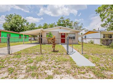 Charming single-story home featuring a red door, covered parking, and a fenced yard at 4812 N 37Th St, Tampa, FL 33610