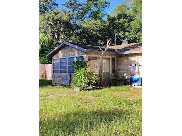 Cozy home with stone siding and a charming sunroom, surrounded by lush greenery at 820 Bayou Ave, Tarpon Springs, FL 34689