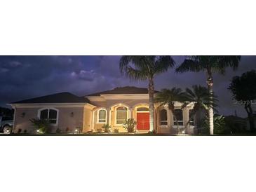 Charming single-story home featuring stucco exterior, a red front door, palm trees and manicured landscaping at 2668 Jablo Cir, North Port, FL 34288