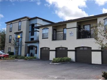 View of the residential apartment building featuring garages and balconies, complemented by lush landscaping at 8413 Lucuya Way # 306, Temple Terrace, FL 33637