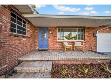 Charming brick home featuring a covered front porch with seating and a blue front door at 307 N Glen Ave, Tampa, FL 33609