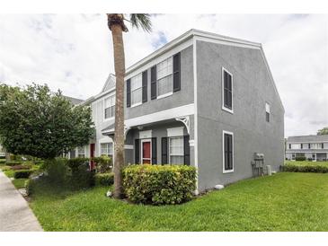 Two-story townhouse featuring a gray stucco exterior, black shutters, and a well-maintained front lawn at 232 Countryside Key Blvd, Oldsmar, FL 34677