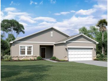 Inviting single-story home with a two-car garage, neutral stucco, horizontal siding, stone accents, and manicured lawn at 14684 Italy Ave, Dade City, FL 33523