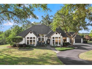 Charming single-story home with manicured landscaping, curved driveway, and large windows at 36846 Perry Ct, Dade City, FL 33525