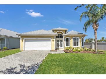 Charming home with a manicured lawn, lush landscaping and a white garage door at 6412 Coquina Island Cv, Apollo Beach, FL 33572