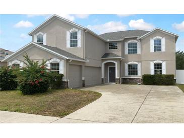 Two-story home featuring neutral stucco, white window trim, an arched entry, and a two car garage at 10768 Carloway Hills Dr, Wimauma, FL 33598