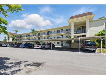 Exterior condo view showing the facade and covered parking on a bright sunny day at 1415 Doolittle Ln # 106, Dunedin, FL 34698