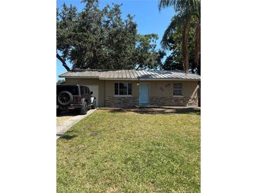 Charming single-story home featuring stone accents, a well-manicured lawn, and a light-blue front door at 1317 W Alicia Ave, Tampa, FL 33604
