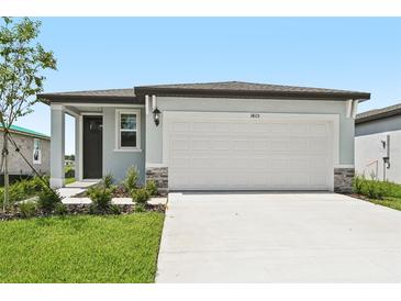 Charming single-story home featuring a two-car garage, well-maintained lawn, and inviting front entrance at 14115 Crutchfield Ct, Parrish, FL 34219