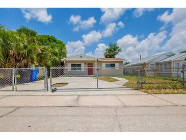 Charming single-story home featuring a red front door, chain-link fence, and inviting curb appeal at 4111 13Th S Ave, St Petersburg, FL 33711