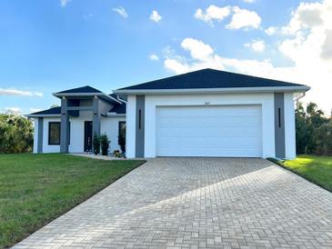 Beautiful single-story home with a well-manicured lawn and long brick driveway, enhancing curb appeal at 267 Santa Marta St, Port Charlotte, FL 33954