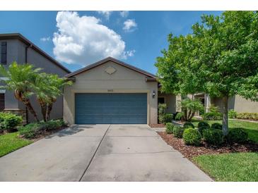 Charming single-story home with a well-maintained lawn, mature trees, and a spacious driveway leading to a blue garage door at 8410 Red Spruce Ave, Riverview, FL 33578