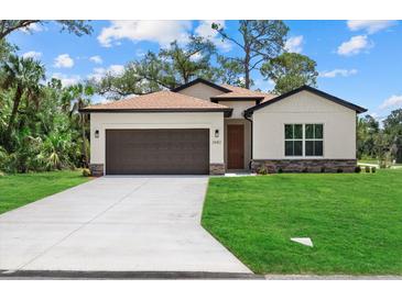 Charming single-Gathering home features a well-manicured lawn, two-car garage, and neutral color scheme at 2682 Edwin Ave, North Port, FL 34288