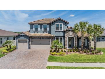 Beautiful two-story home featuring a stone facade, tile roof, three-car garage, and well-manicured landscaping at 29043 Picana Ln, Wesley Chapel, FL 33543