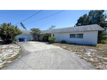 Single story home with white painted facade, long driveway, attached garage, and tidy landscaping at 4719 Alcazar S Way, St Petersburg, FL 33712
