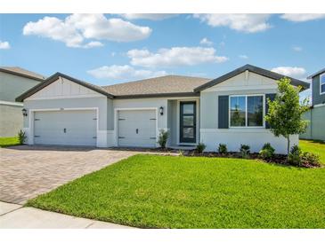 Beautiful single-Gathering home with a well-maintained lawn, a brick driveway, and a three-car garage at 1780 Draughton Dr, Zephyrhills, FL 33541