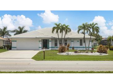 Charming single-story home with well-manicured lawn, white tile roof, and tropical landscaping with palm trees at 260 Coronado Dr, Punta Gorda, FL 33950