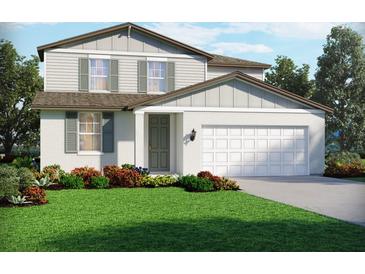 Charming two-story home featuring white stucco, sage shutters, manicured lawn, and an attached two-car garage at 1740 Brekey Way, Zephyrhills, FL 33541