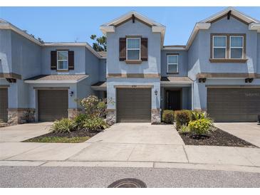Charming two-story townhome with blue exterior, brown trim, attached garage, and landscaped yard at 6703 Citrus Creek Ln, Tampa, FL 33625