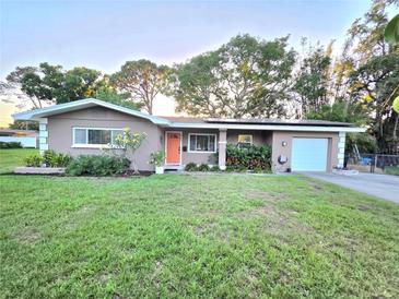Charming one-story home with a well-manicured lawn, an orange front door, and lush landscaping at 663 68Th S Ave, St Petersburg, FL 33705