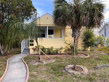Charming yellow home featuring a well-manicured front yard with lovely palm trees at 1834 28Th N Ave, St Petersburg, FL 33713