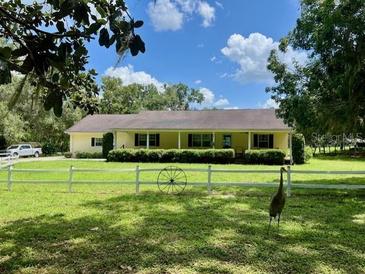 Sprawling ranch-style home with white picket fence and lush green lawn at 17380 Sweetwater Rd, Dade City, FL 33523