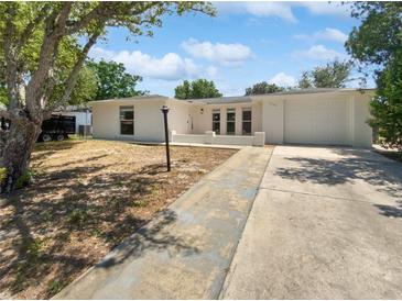 Charming single-story home featuring a driveway and well-maintained front yard under a blue sky at 7604 Tyson Dr, Port Richey, FL 34668