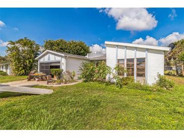 Quaint home featuring white paint, gray trim, and a garage with a screened door at 18430 Alphonse Cir, Port Charlotte, FL 33948