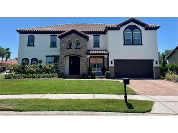 Charming two-story home with a tile roof, stone accents, well-manicured lawn, and a two car garage at 302 Coco Plum Ct, Oldsmar, FL 34677