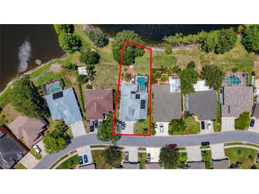 Aerial view of a single Gathering home with a pool and a well-manicured lawn, surrounded by lush greenery and a pond at 1913 Blue River Rd, Holiday, FL 34691