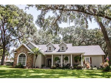 Charming single-story home with stone accents, dormers and a welcoming front porch, surrounded by mature trees and lush landscaping at 2906 Country Breeze Dr, Plant City, FL 33567