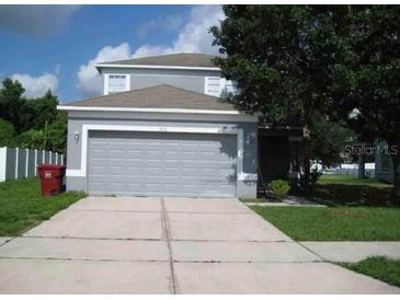 Two-story home with a gray exterior, attached garage, driveway and verdant landscaping at 3517 Trapnell Ridge Dr, Plant City, FL 33567