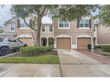 Two-story townhome with brown shutters, a garage, and a well-manicured lawn at 26622 Castleview Way, Wesley Chapel, FL 33544