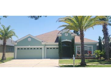 Charming one-story home featuring a three-car garage, manicured lawn, and mature palm trees at 1829 Mira Lago Cir, Ruskin, FL 33570