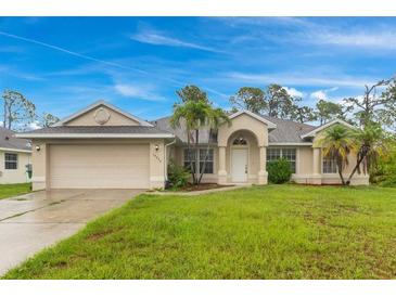 Charming single-story home with a well-maintained lawn, a two car garage and lovely landscaping with palm trees at 14256 Salvatierra Ln, Port Charlotte, FL 33981