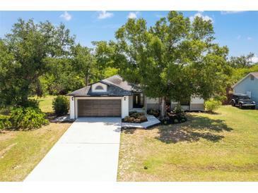 Charming single-story home with a two-car garage, mature trees, and well-maintained landscaping at 19543 Midway Blvd, Port Charlotte, FL 33948
