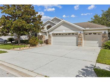 Charming single-story home featuring a three-car garage, stone accents, and well-maintained landscaping at 6935 Runner Oak Dr, Wesley Chapel, FL 33545