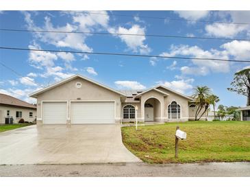 Beautiful single-story home with a two-car garage, lush lawn, and a welcoming arched entryway with decorative windows at 924 Texas St, Englewood, FL 34223